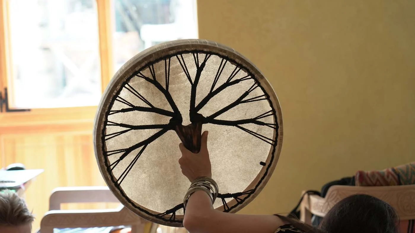 A frame drum with a tree motif held towards the light